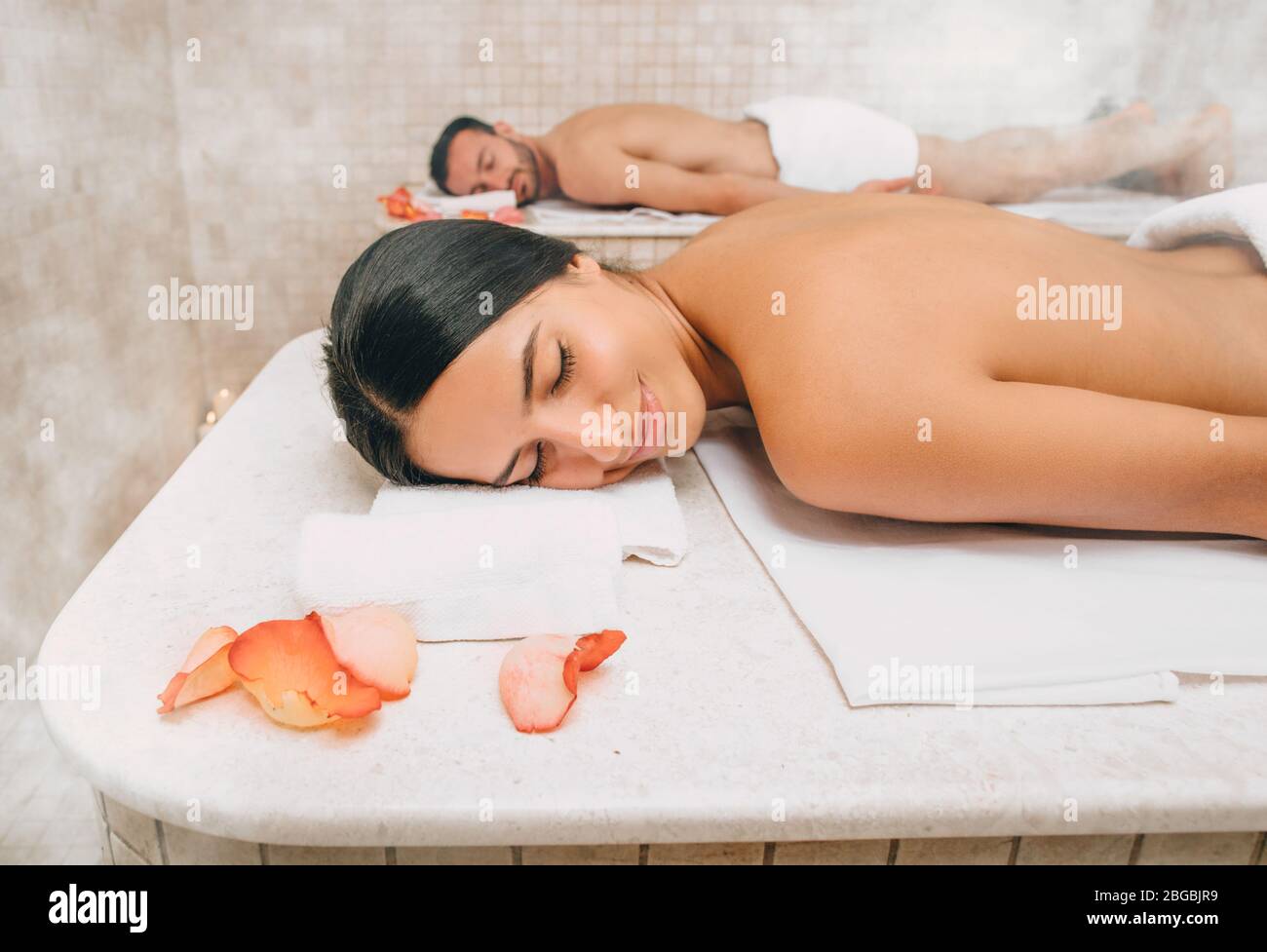 Belle femme et son petit ami se trouvent sur des tables de massage au hammam chaud avant les procédures de lavage du corps. Bain turc pour couple Banque D'Images