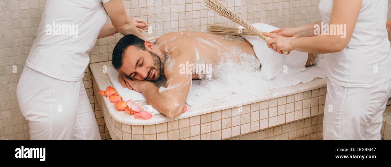 Un turc qui se fait masser avec un balai de bambou au spa. Un ouvrier du hammam lave la peau des hommes dans le hammam Banque D'Images