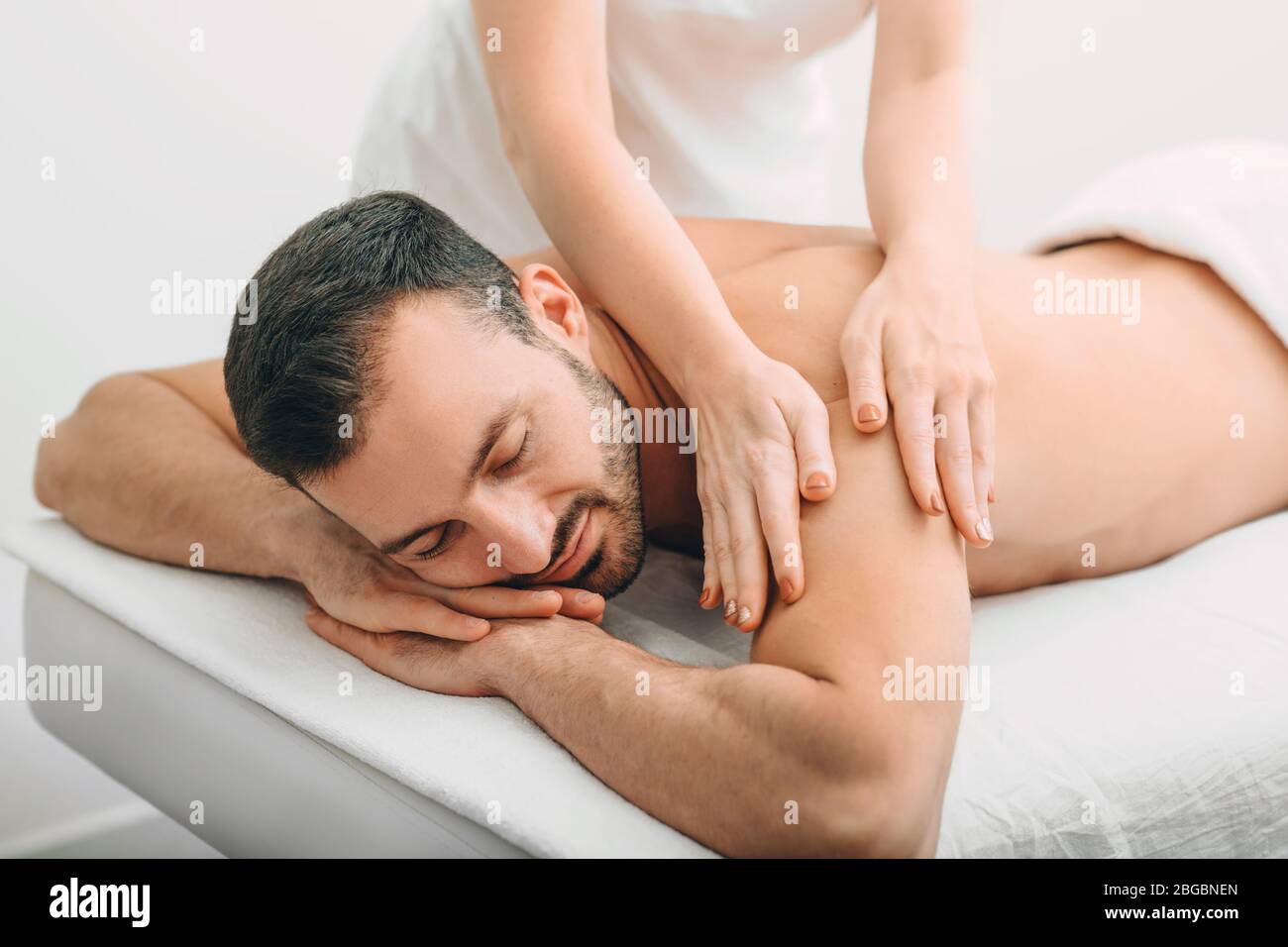 un homme bien situé qui profite d'un massage du dos, d'un spa le week-end. un homme de course mixte se détend pendant un massage du dos Banque D'Images