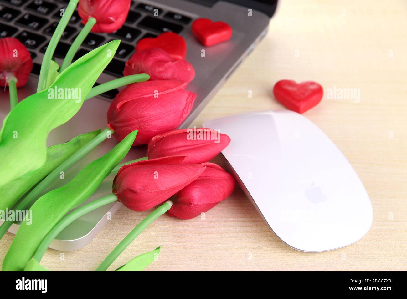 Ordinateur avec coeurs rouges et fleurs sur la table près Banque D'Images
