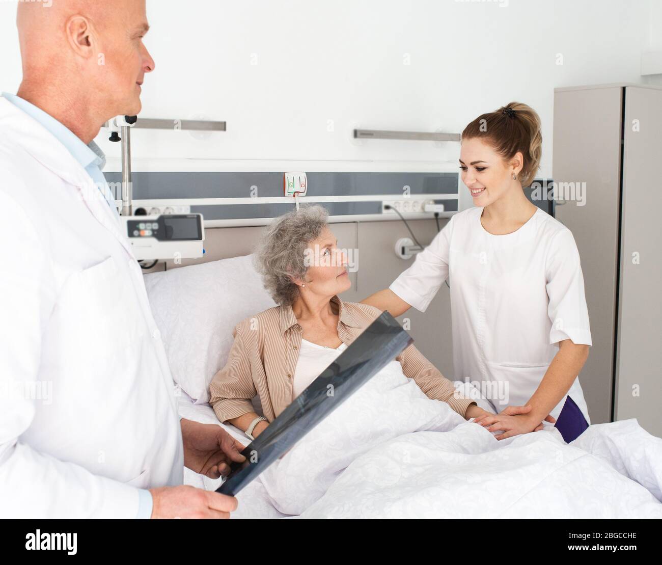 un patient âgé reçoit le soutien d'une infirmière tout en restant dans un lit d'hôpital. Soins aux patients âgés Banque D'Images