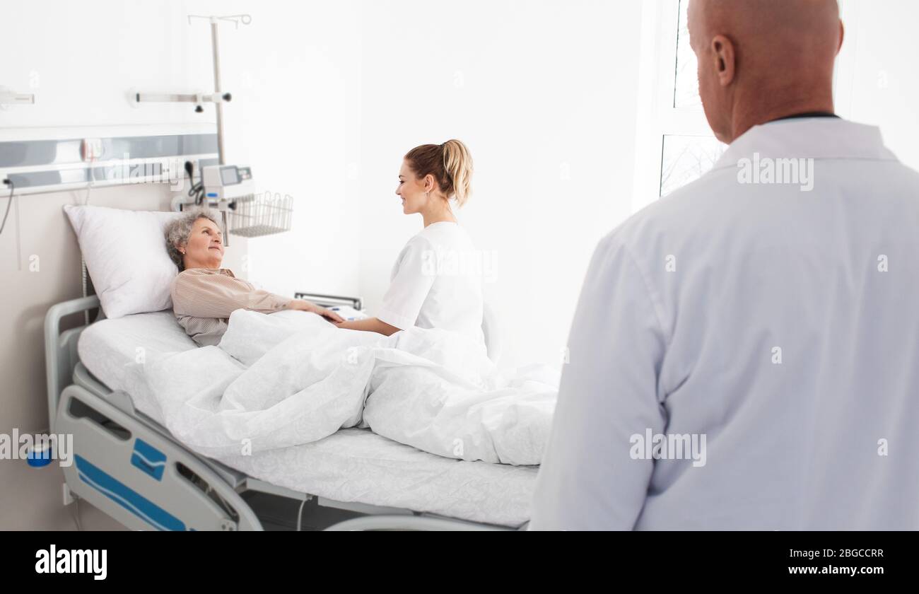 Soins médicaux aux personnes âgées. patient âgé couché dans un lit d'hôpital, ayant un soutien infirmier. Traitement clinique et soins aux personnes âgées Banque D'Images