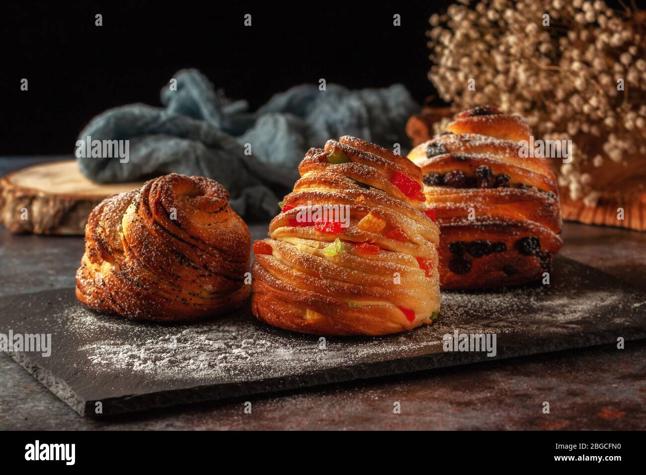 Kraffins aux raisins secs, fruits confits et graines de pavot, arrosés de sucre en poudre. Banque D'Images