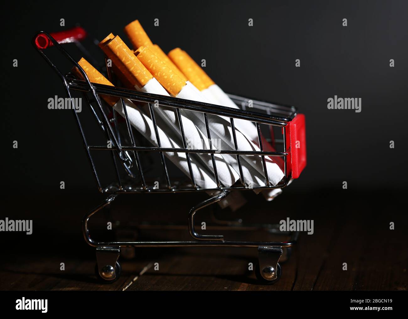 Cigarettes dans le panier sur table en bois sur fond gris foncé Banque D'Images