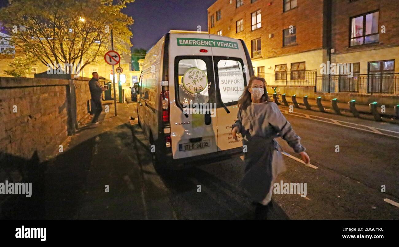 Intérieur de la ville aider le volontaire sans-abri avril sombre mains hors des boissons chaudes, de la nourriture et des articles de toilette aux sans-abri et les traverses rugueuses dans le centre de Dublin pendant le verrouillage du coronavirus. Banque D'Images