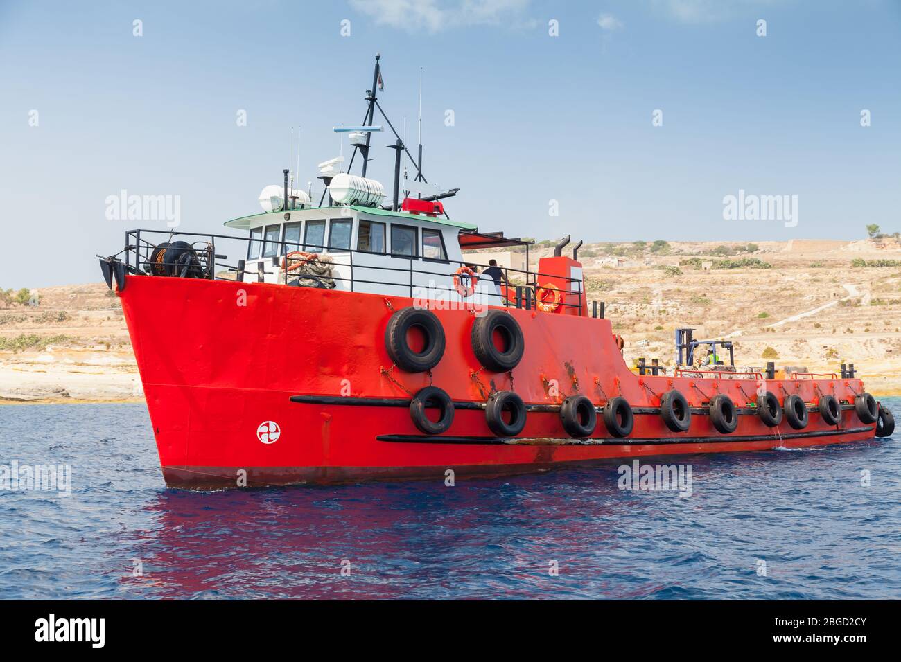 Bateau remorqueur avec coque rouge vif va près de l'île de Malte le jour ensoleillé Banque D'Images