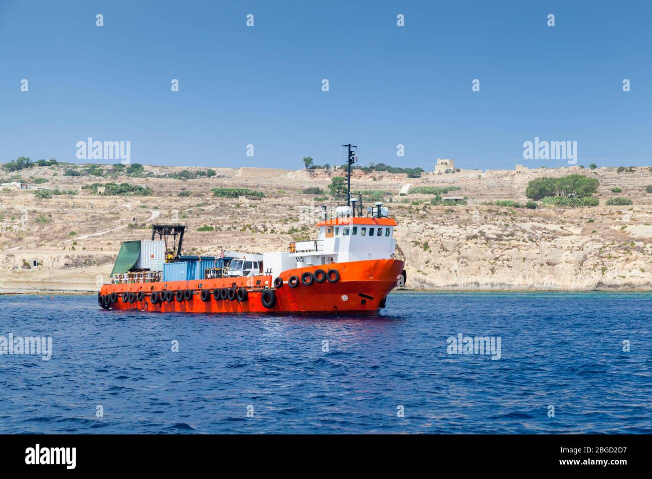 Fret maritime, un bateau remorqueur avec coque rouge va à la mer Méditerranée près de l'île de Malte à la journée ensoleillée d'été Banque D'Images