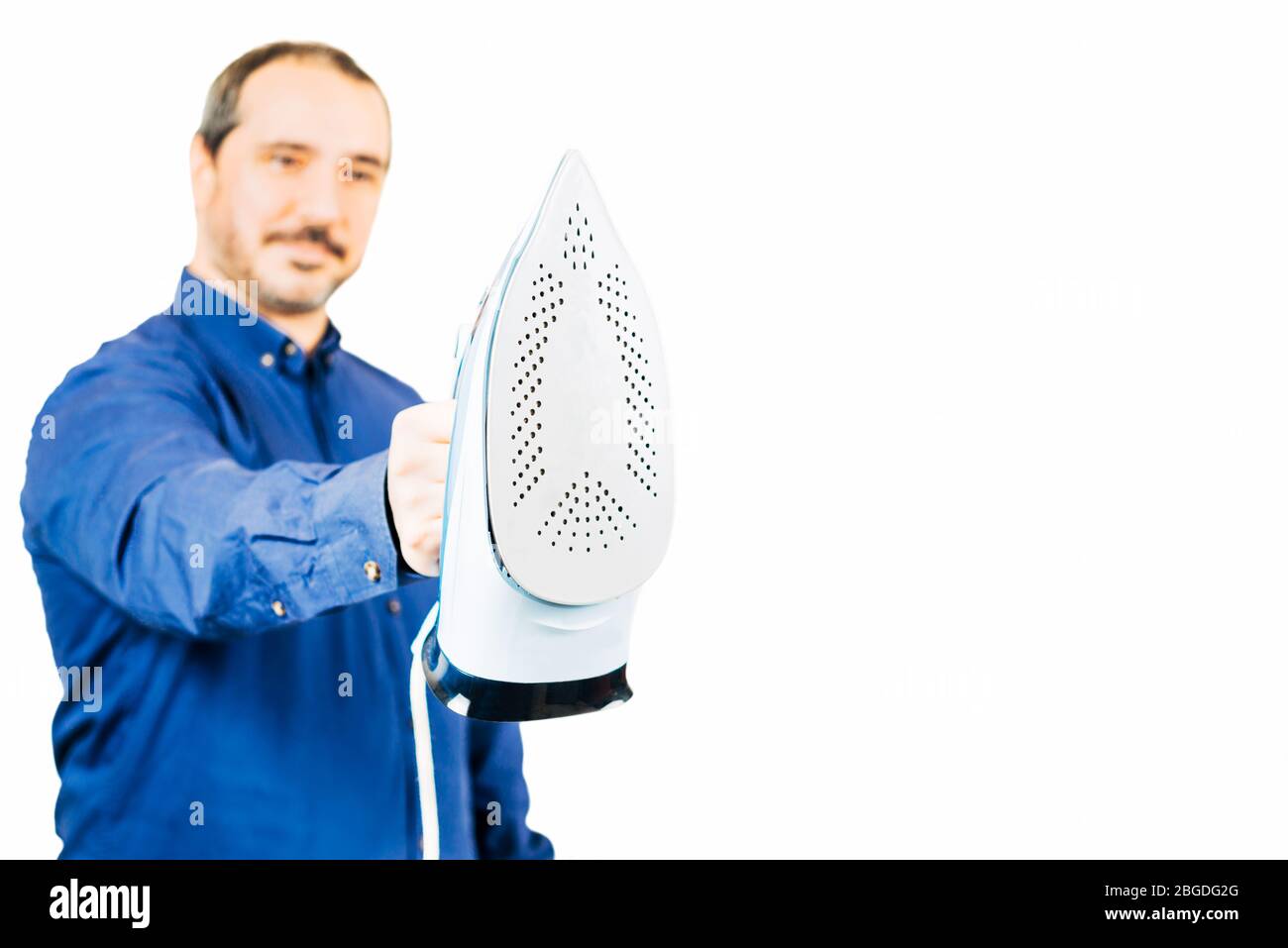 homme dans une chemise bleue tenant un fer sur fond blanc Banque D'Images