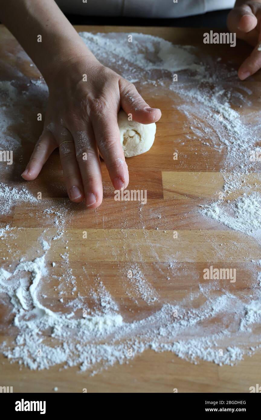 Concept de cuisine maison. Mains féminines préparant de petites boules de pâte à pizza maison fraîche sur planche en bois farinée. Gros plan. Cuisine italienne. Banque D'Images