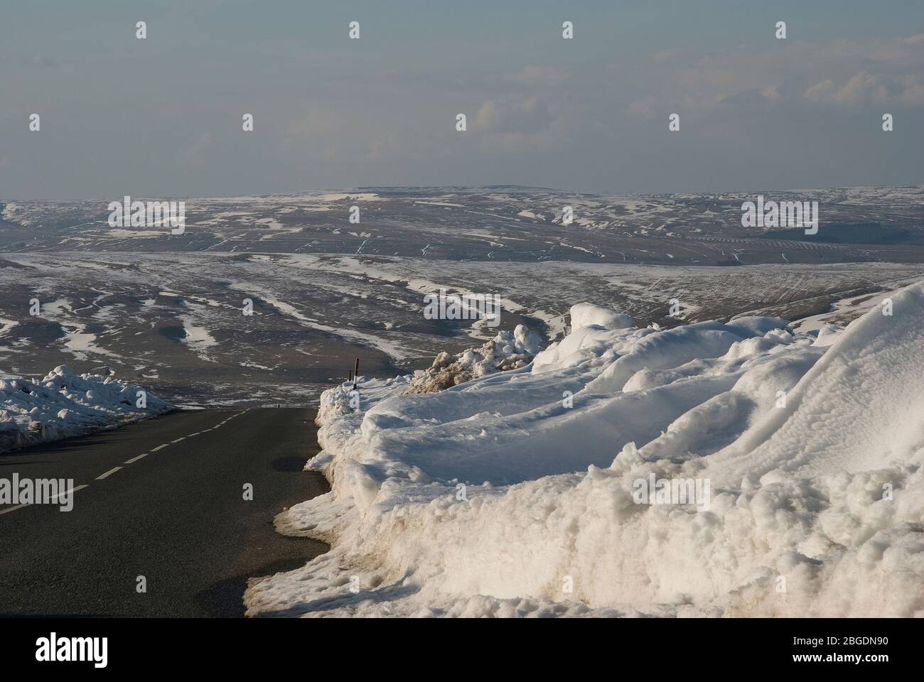 Route traversant les landes sur la frontière Weardale - Teesdale dans le comté de Durham en hiver avec de la neige empilée au bord de la route après le labour de neige Banque D'Images
