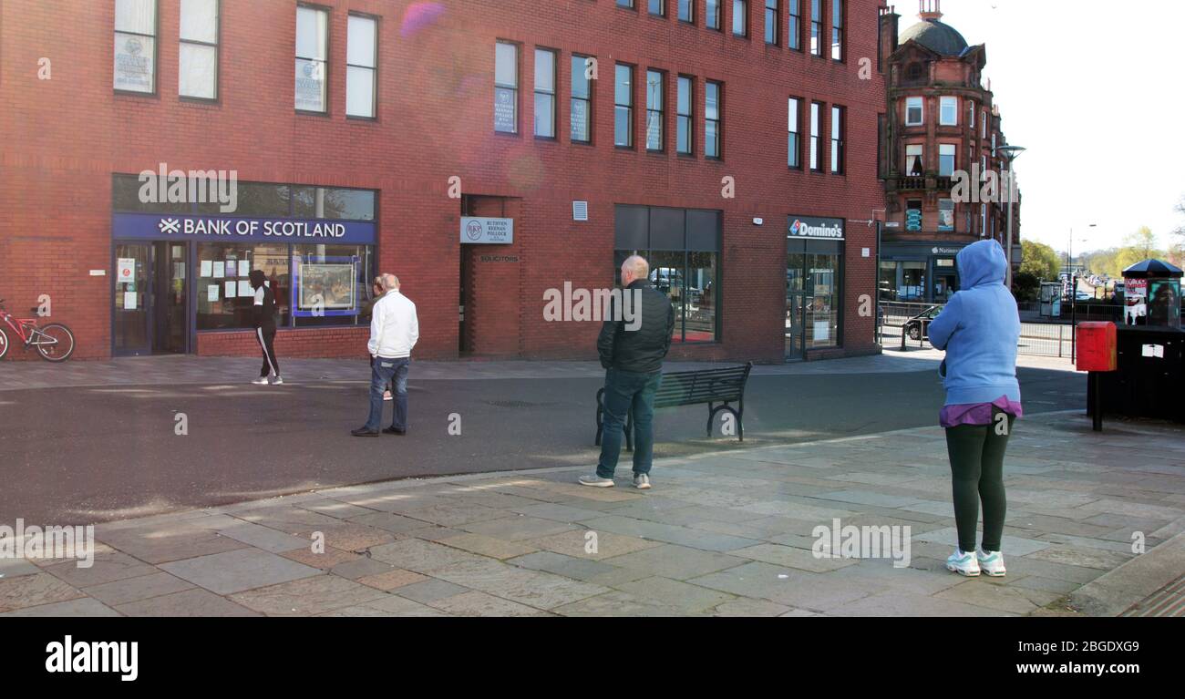 Les gens font la queue dans des distances sociales strictes de 2 mètres ou plus en attendant d'aller à une machine à argent liquide dans une banque, les mesures d'autofinancement sont en place en raison de la pandémie de Covid-19 et de coronavirus qui fait rage en Grande-Bretagne. Il a provoqué une situation de verrouillage, Glasgow. Avril 2020. ALAN WYLIE/ALAY© Banque D'Images