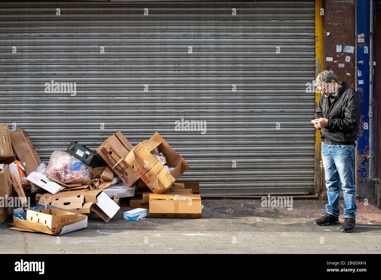 Un homme debout à côté d'une pile de boîtes en carton sur Electric Avenue, Brixton, Londres Banque D'Images