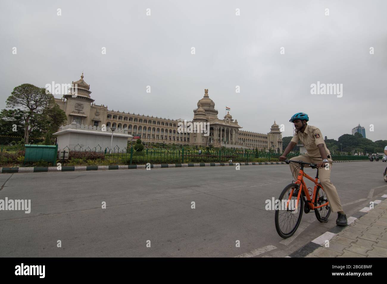 Un policier en cycle portant un casque de cyclisme devant le bâtiment législatif/administratif "Vidhana Soudha" un matin nuageux Banque D'Images