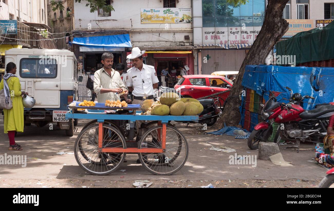 Une police de la circulation vérifiant les gros fruits vendus par un fauteur de rue près du marché de Russel pendant la journée Banque D'Images
