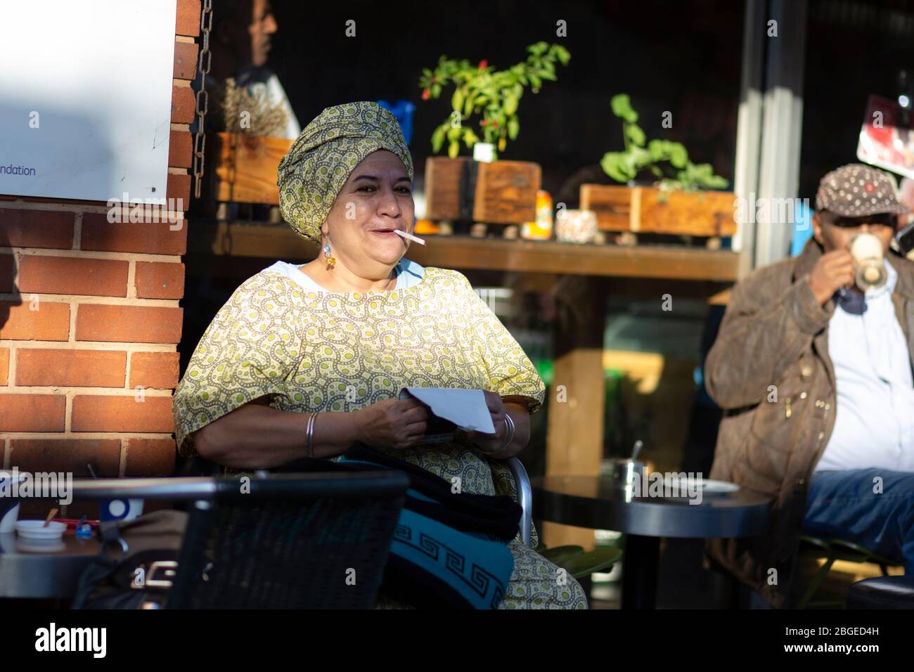 Une femme qui fume devant un café sur Brixton Station Road, Londres Banque D'Images