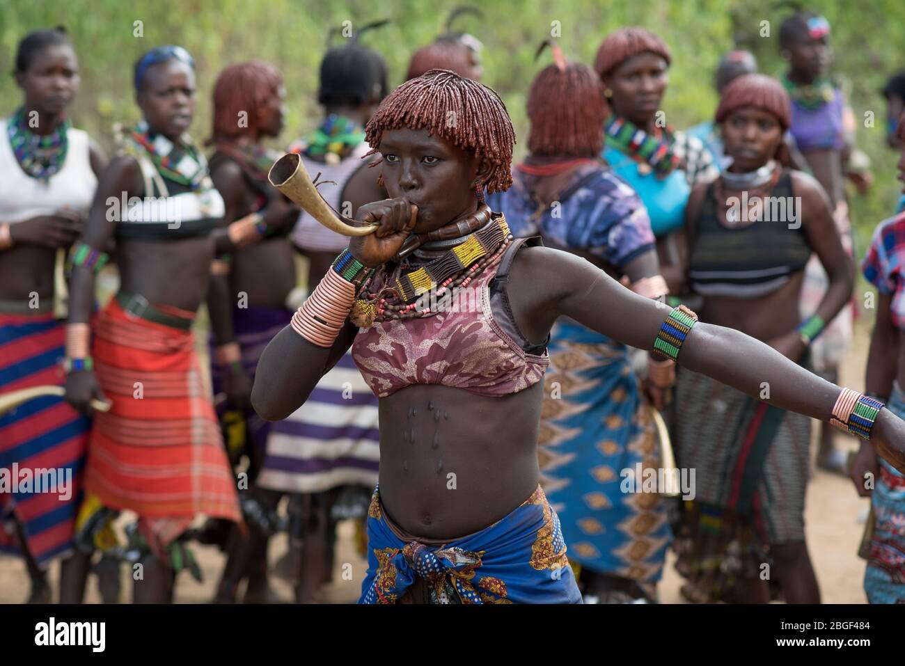 Les femmes dansent les cornes de laiton au groupe ethnique de la tribu de Morsi à l'âge de la cérémonie de saut à taureaux, Jenka, Ethiopie. Banque D'Images