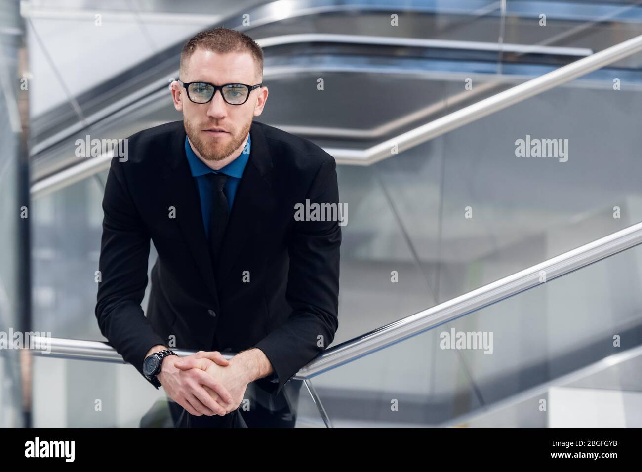 Élégant jeune homme adulte debout sur les escaliers avec sac à main. Il regarde la caméra Banque D'Images