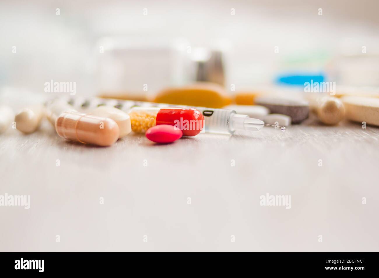 Écureuils aiguilles de seringue avec médicaments sur pilules multicolores et ampoules sur fond de table blanc Banque D'Images