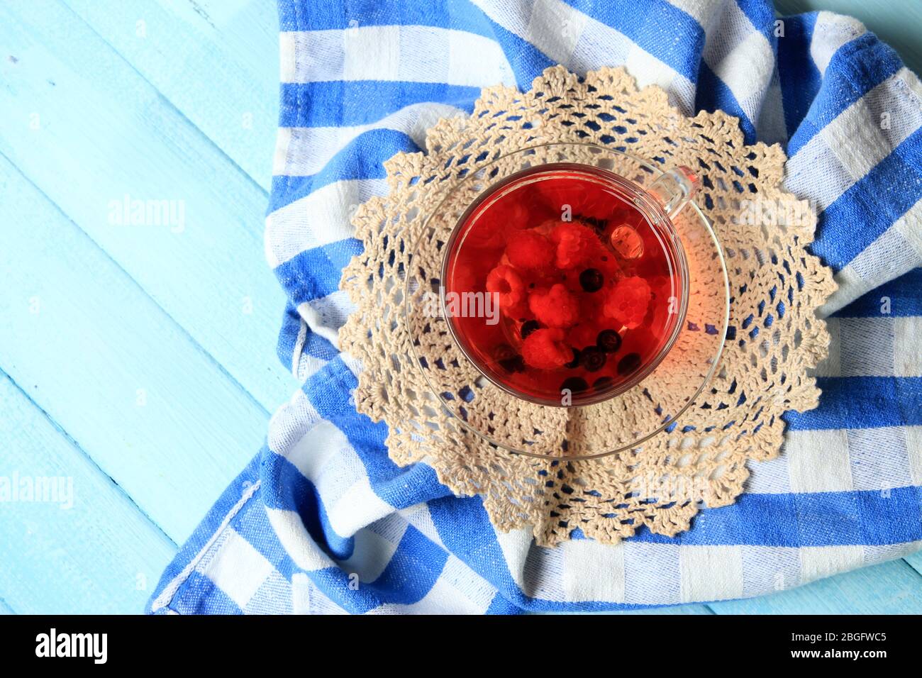 Thé rouge aux fruits avec baies sauvages dans une tasse en verre, sur fond en bois Banque D'Images