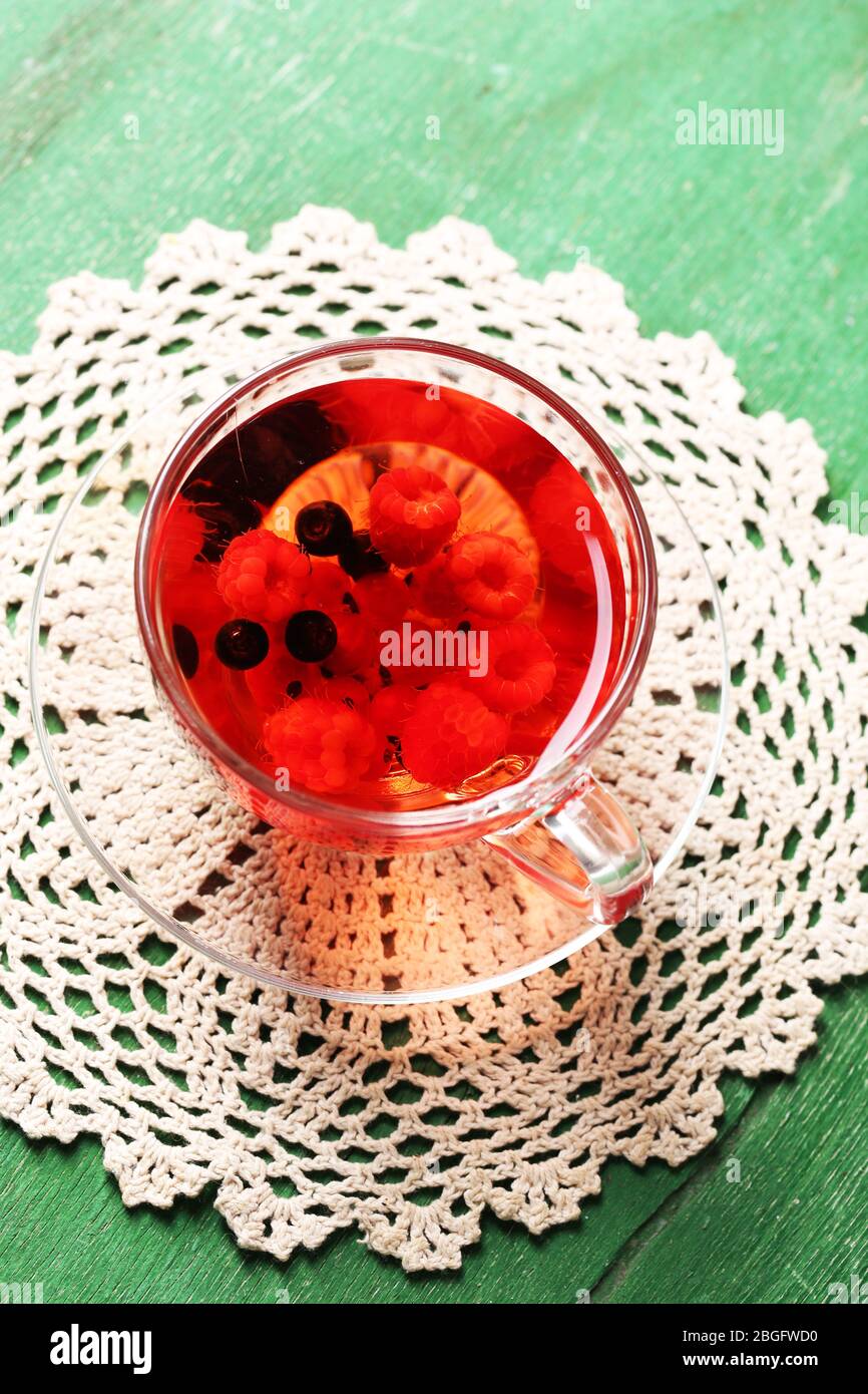 Thé rouge aux fruits avec baies sauvages dans une tasse en verre, sur fond en bois Banque D'Images