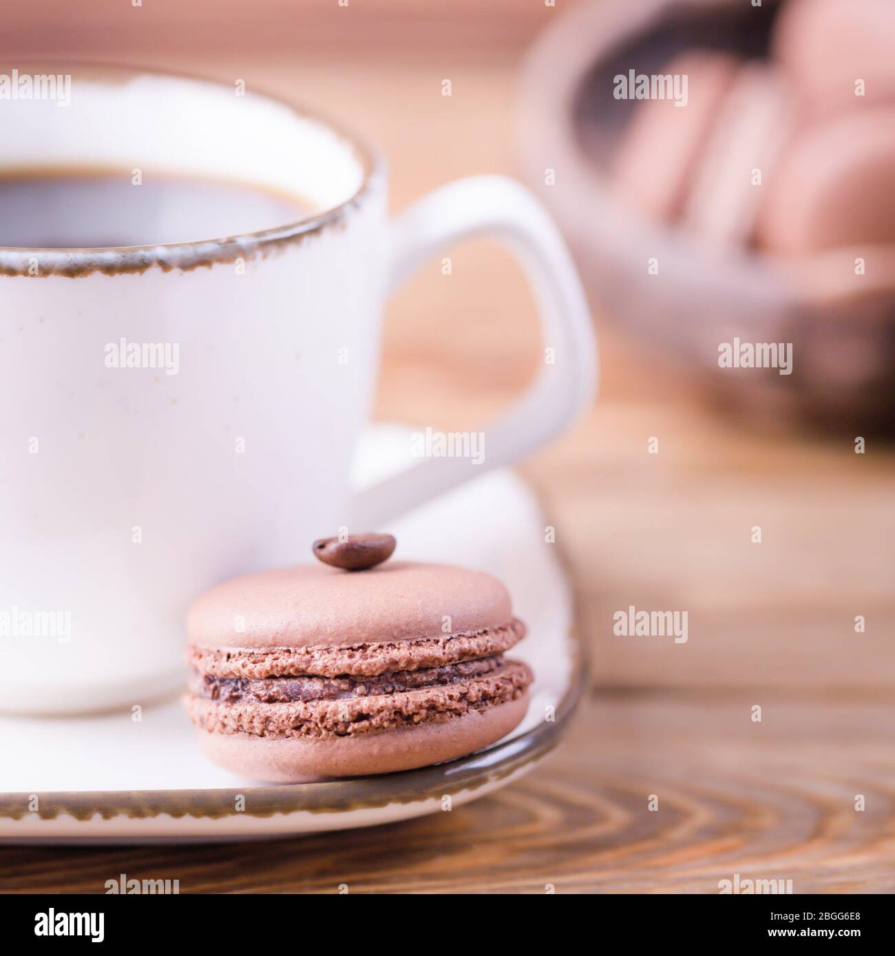 Du café noir et français dessert macarons au chocolat avec grain de café sur un fond de bois Banque D'Images