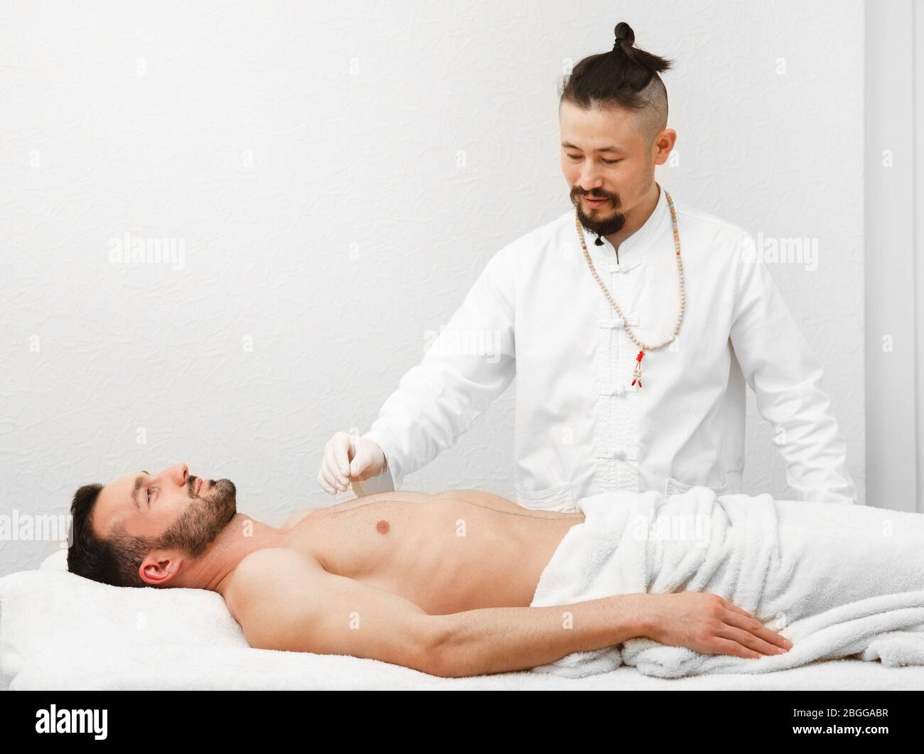 Acupuncturist insère des aiguilles d'acupuncture à des points spéciaux sur les méridiens du corps d'un homme. Médecine alternative, traitement des aiguilles Banque D'Images