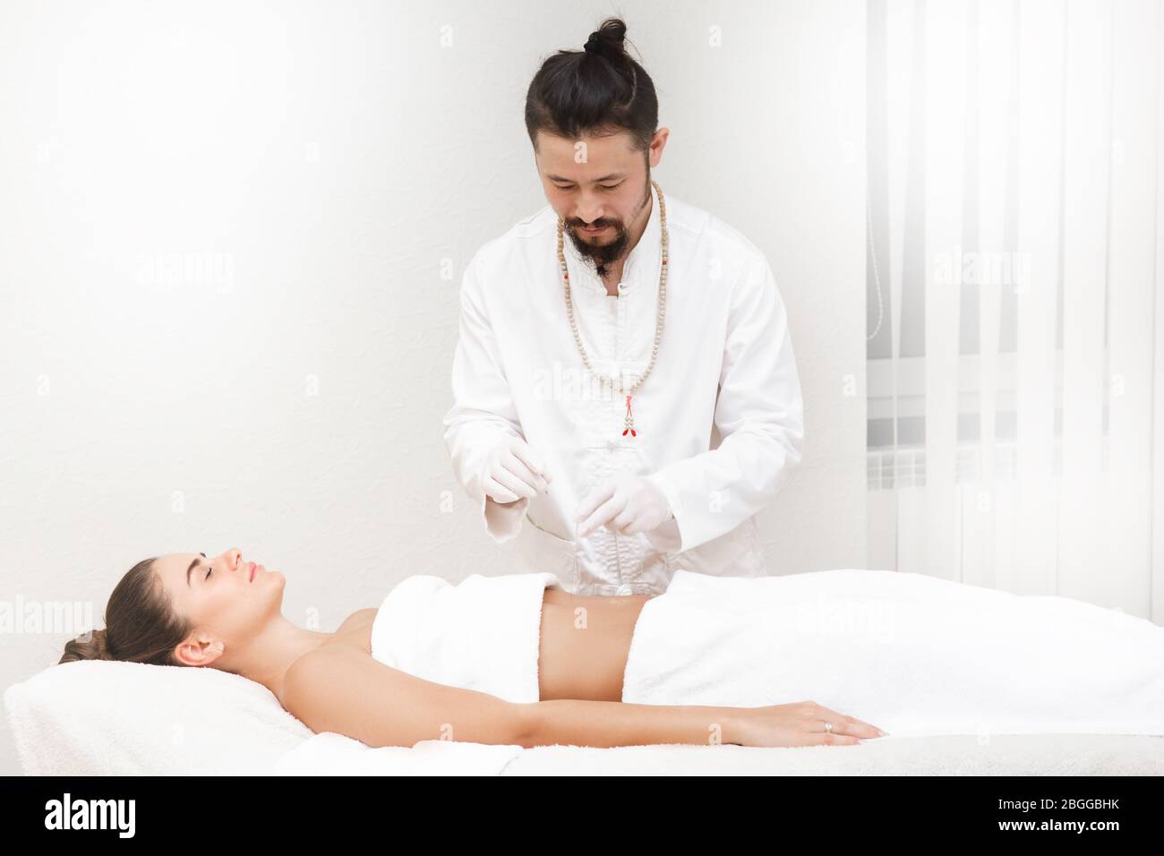 Médecin de médecine orientale faisant des estomacs d'acupuncture pour soulager la douleur d'estomac d'une femme. La femme aime l'acupuncture Banque D'Images