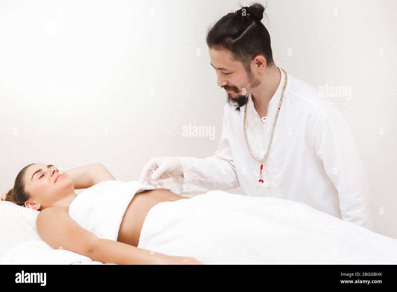 Médecin de médecine orientale faisant des estomacs d'acupuncture pour soulager la douleur d'estomac d'une femme. Médecine alternative Banque D'Images