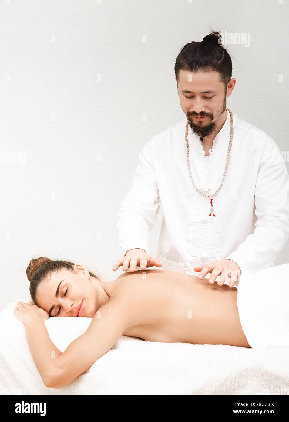 docteur en médecine orientale traditionnelle faisant un massage énergétique sans contact à une belle femme dans un salon de spa. Le corps est nettoyé de l'ener négatif Banque D'Images