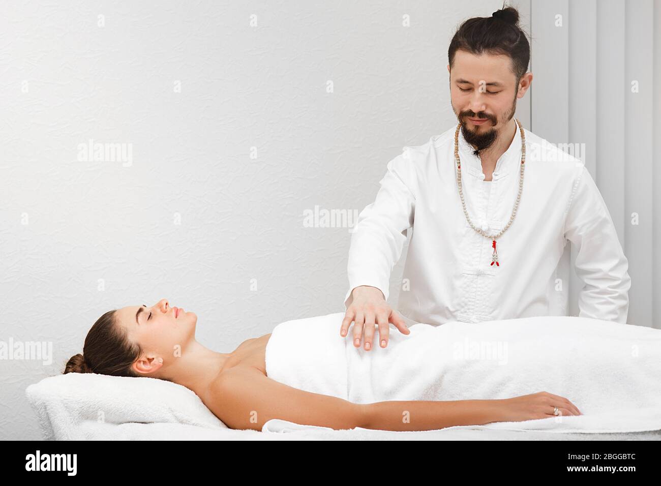 docteur race asiatique faisant massage corporel énergique. Femme recevant une thérapie reiki. Médecine alternative Banque D'Images