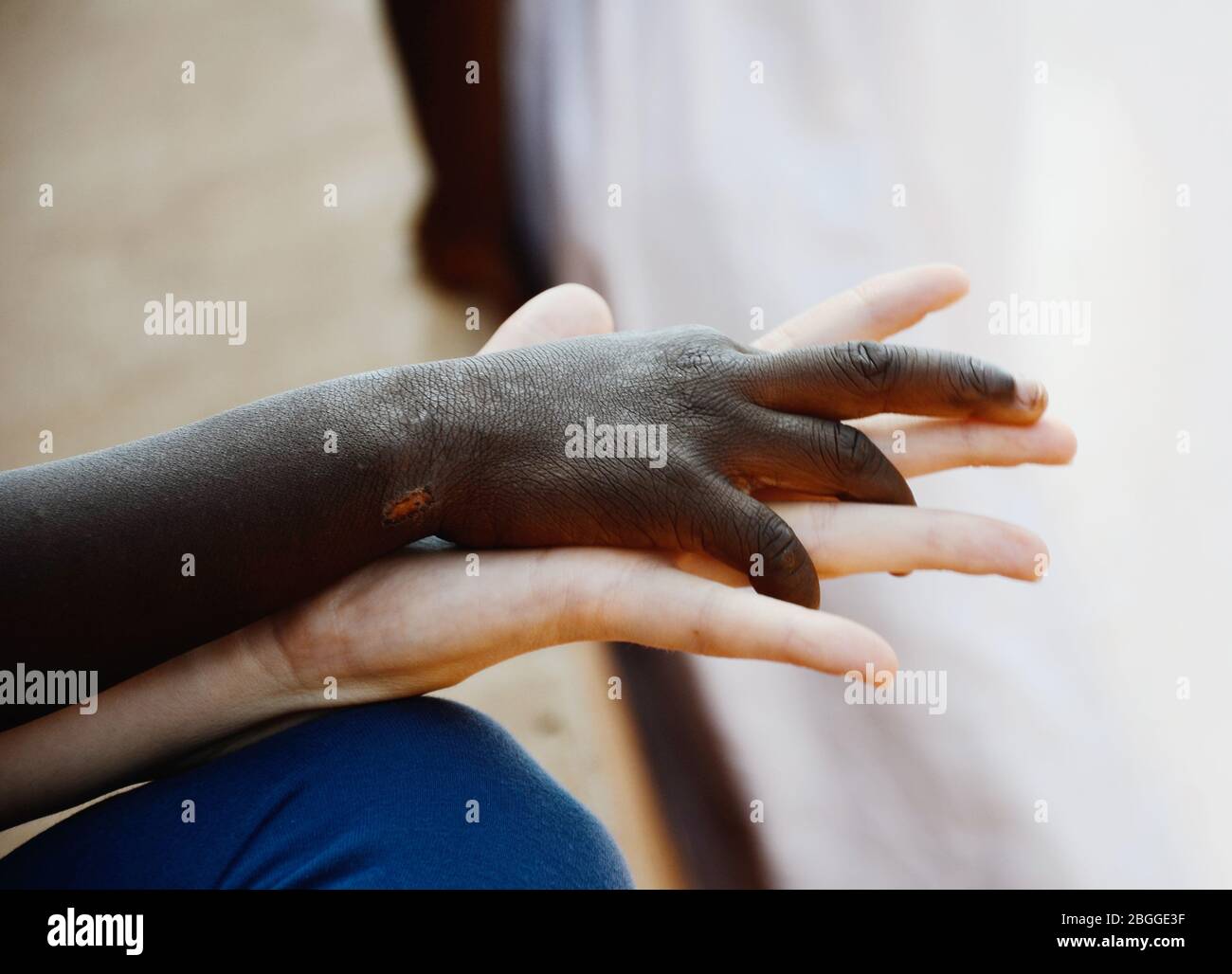 Belle image des droits de l'homme questions: Femme blanche et enfant noir tenant les mains dans un signe d'amour. Banque D'Images