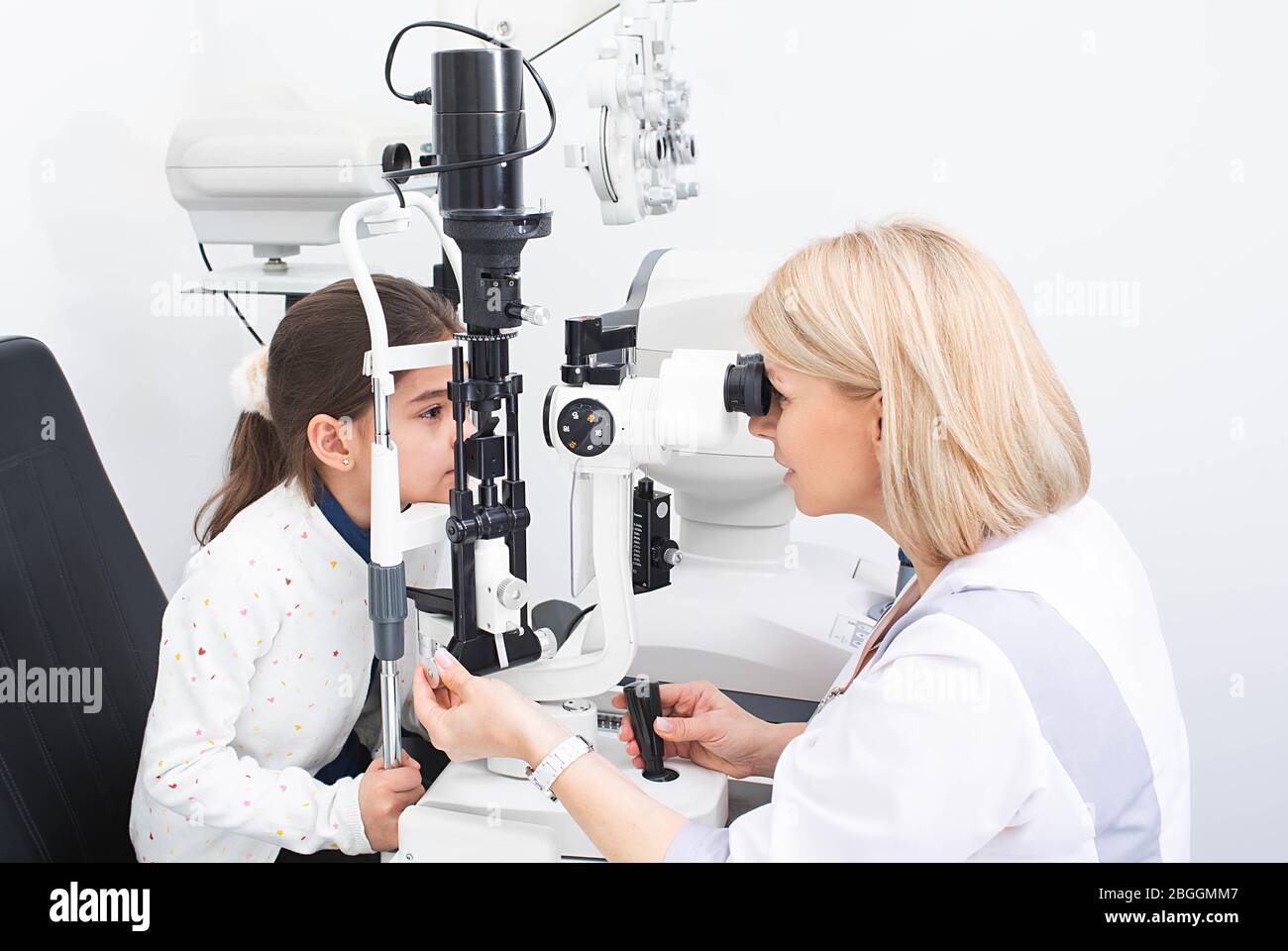 Le médecin optométriste utilisant une lampe à fente binoculaire examine l'œil d'une fille de patient. Les enfants doivent être testés par un ophtalmologiste Banque D'Images