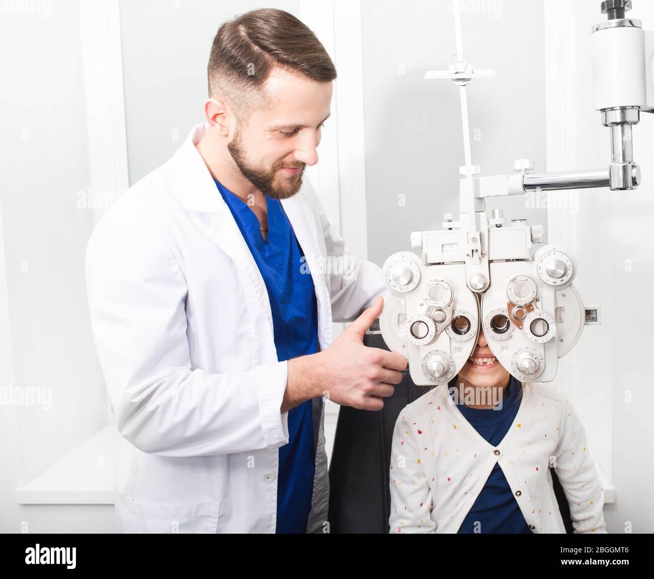 Optométriste médecin vérifie la vue de la jeune fille sur le pforopter. Si la fille a une mauvaise vue, le médecin donnera une ordonnance pour les verres Banque D'Images