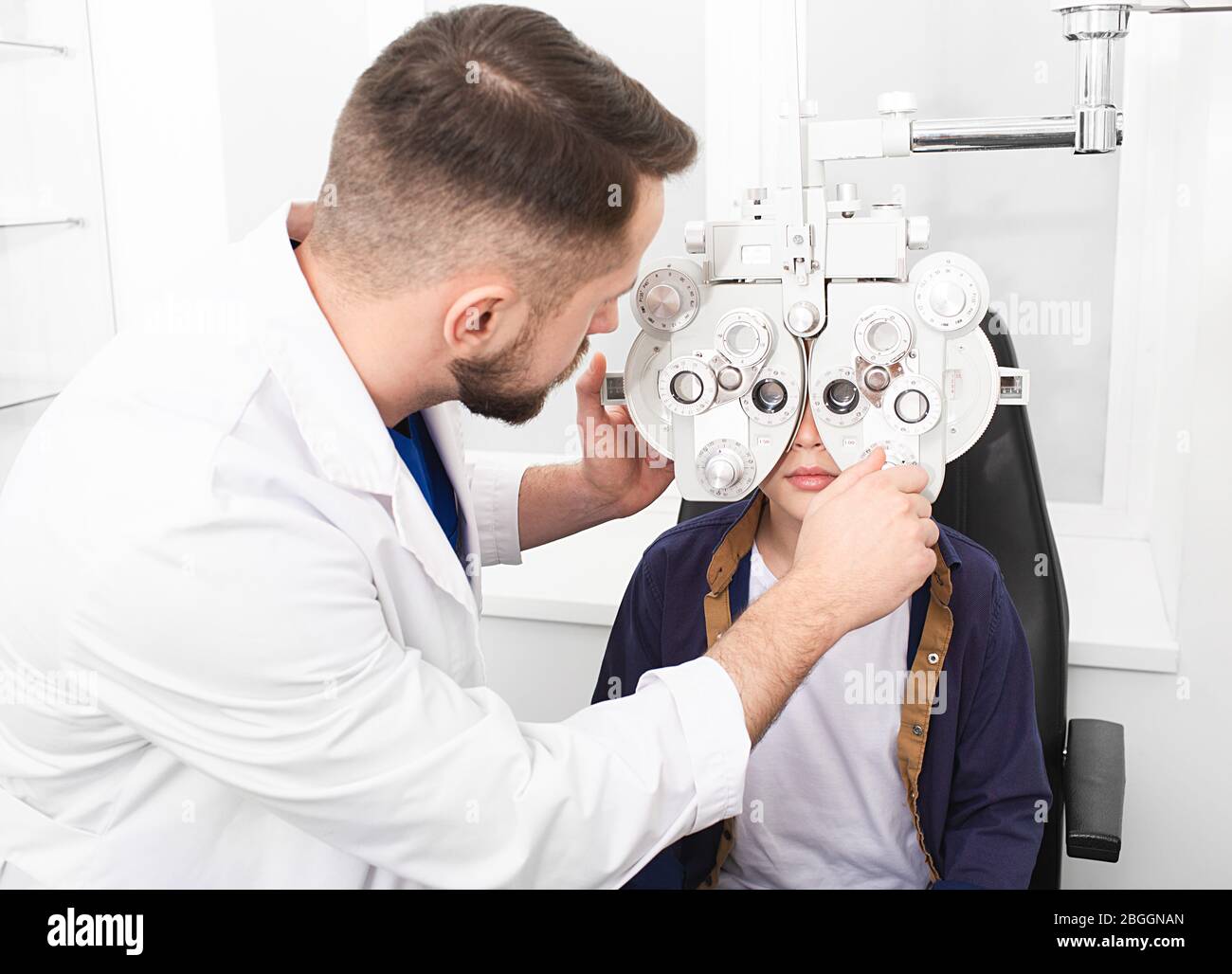 Le médecin optométriste vérifie la vue de l'adolescent. Si le garçon a un mauvais oeil, le médecin donnera une ordonnance pour les verres Banque D'Images