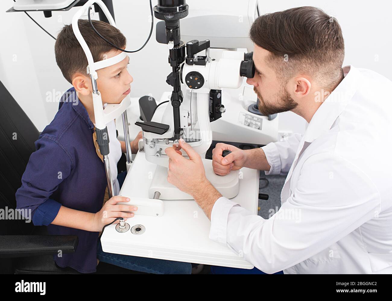 L'ophtalmologiste mâle vérifie la vue d'un adolescent à l'aide d'une lampe à fente binoculaire. Vérification de la vue chez les enfants Banque D'Images