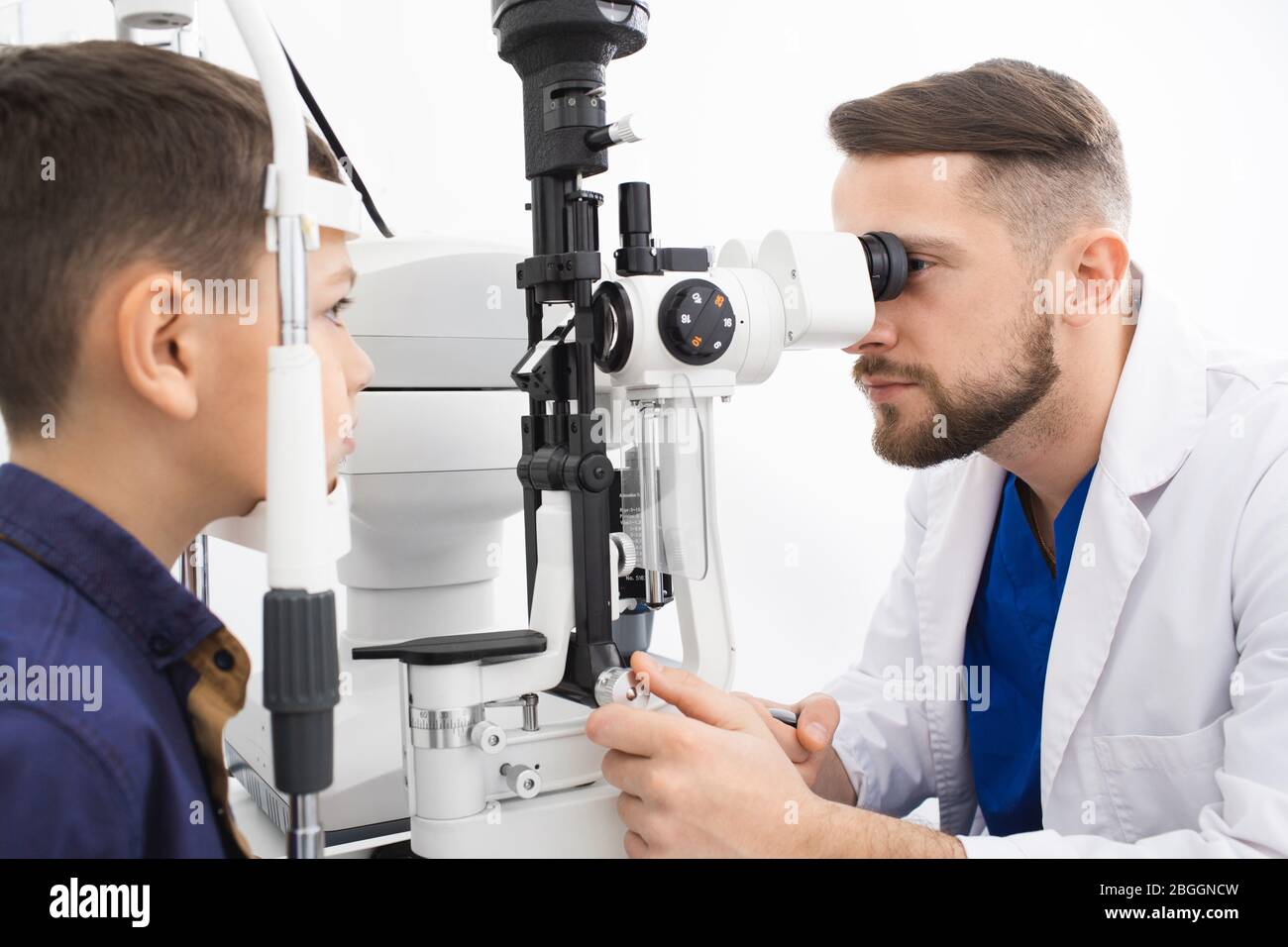 Un médecin expérimenté vérifie la vue d'un adolescent. Clinique moderne pour la vérification et le traitement de la vue Banque D'Images