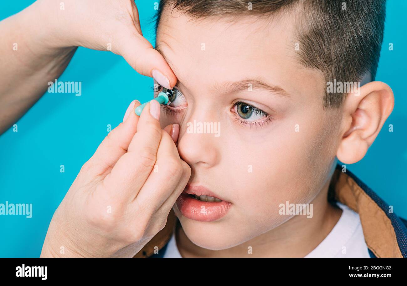 Lentilles de contact pour la correction de la vision chez les enfants.  Ophtalmologiste mettant sur la lentille de contact à un adolescent. Gros  plan de l'objectif de contact sur un fond bleu