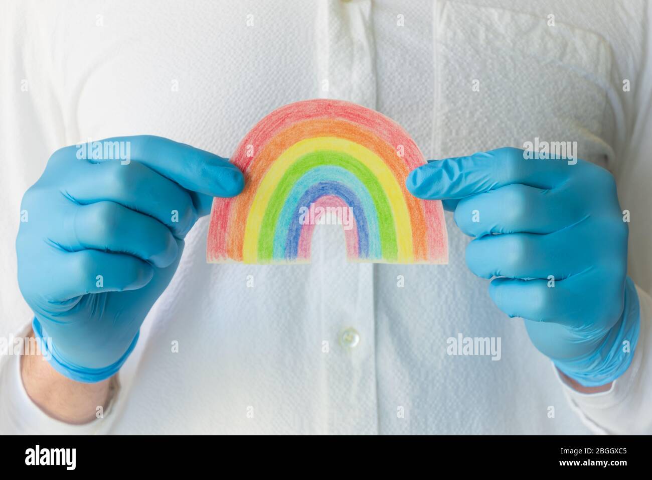 Homme dans un gant médical bleu montrant l'affiche arc-en-ciel dessinée à la main. Merci au personnel du NHS pour votre service face au concept de crise du coronavirus dans le monde entier. Banque D'Images Homme dans un gant médical bleu montrant l'affiche arc-en-ciel dessinée à la main. Merci au personnel du NHS pour votre service face au concept de crise du coronavirus dans le monde entier. Banque D'Images