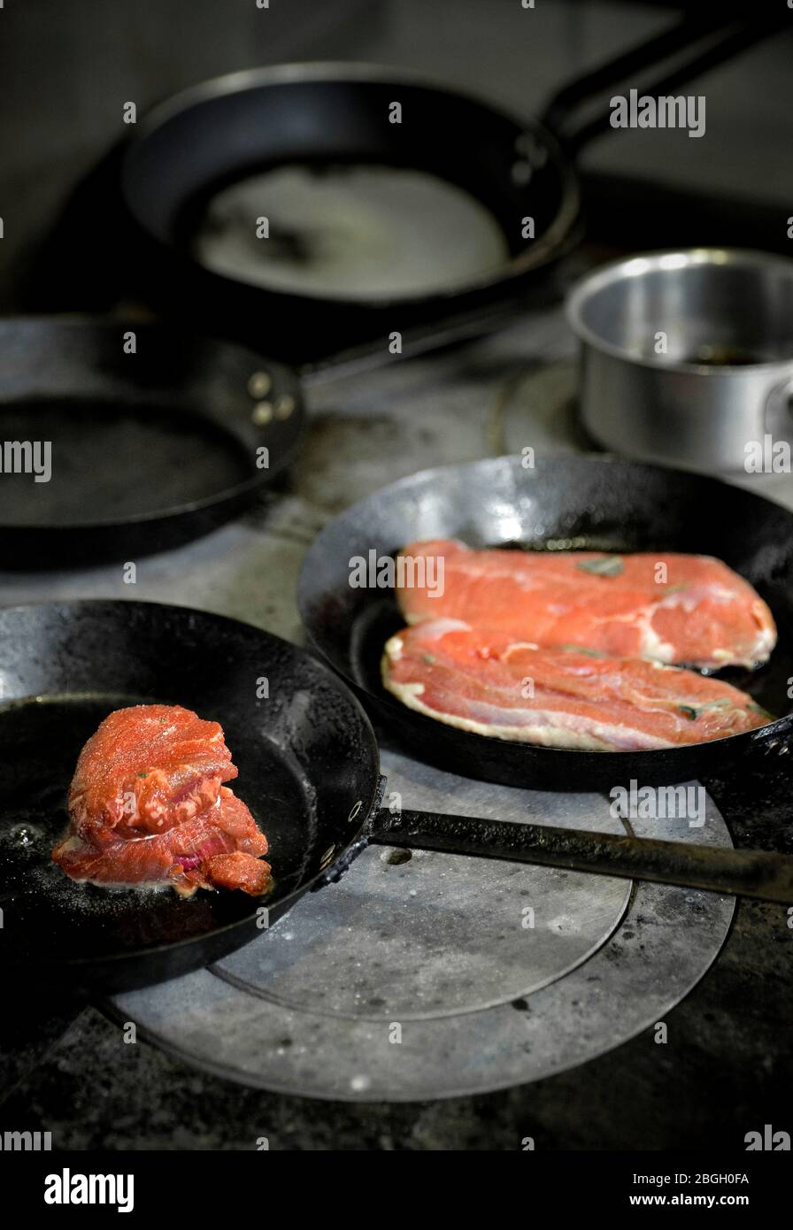 Cuisine de biftecks dans des casseroles dans la cuisine de restaurant Banque D'Images