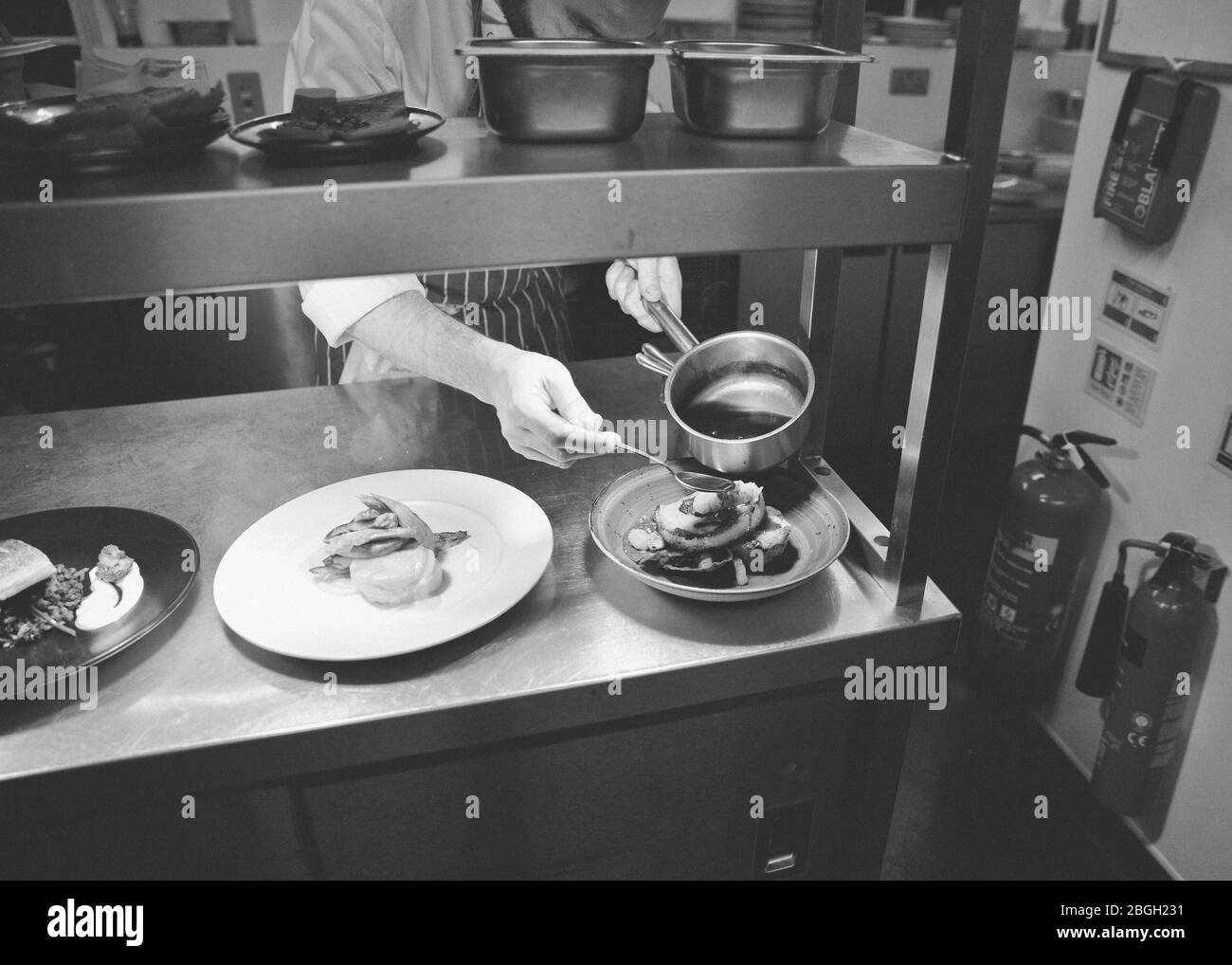 Chef verser de la sauce sur la nourriture dans la cuisine du restaurant Banque D'Images