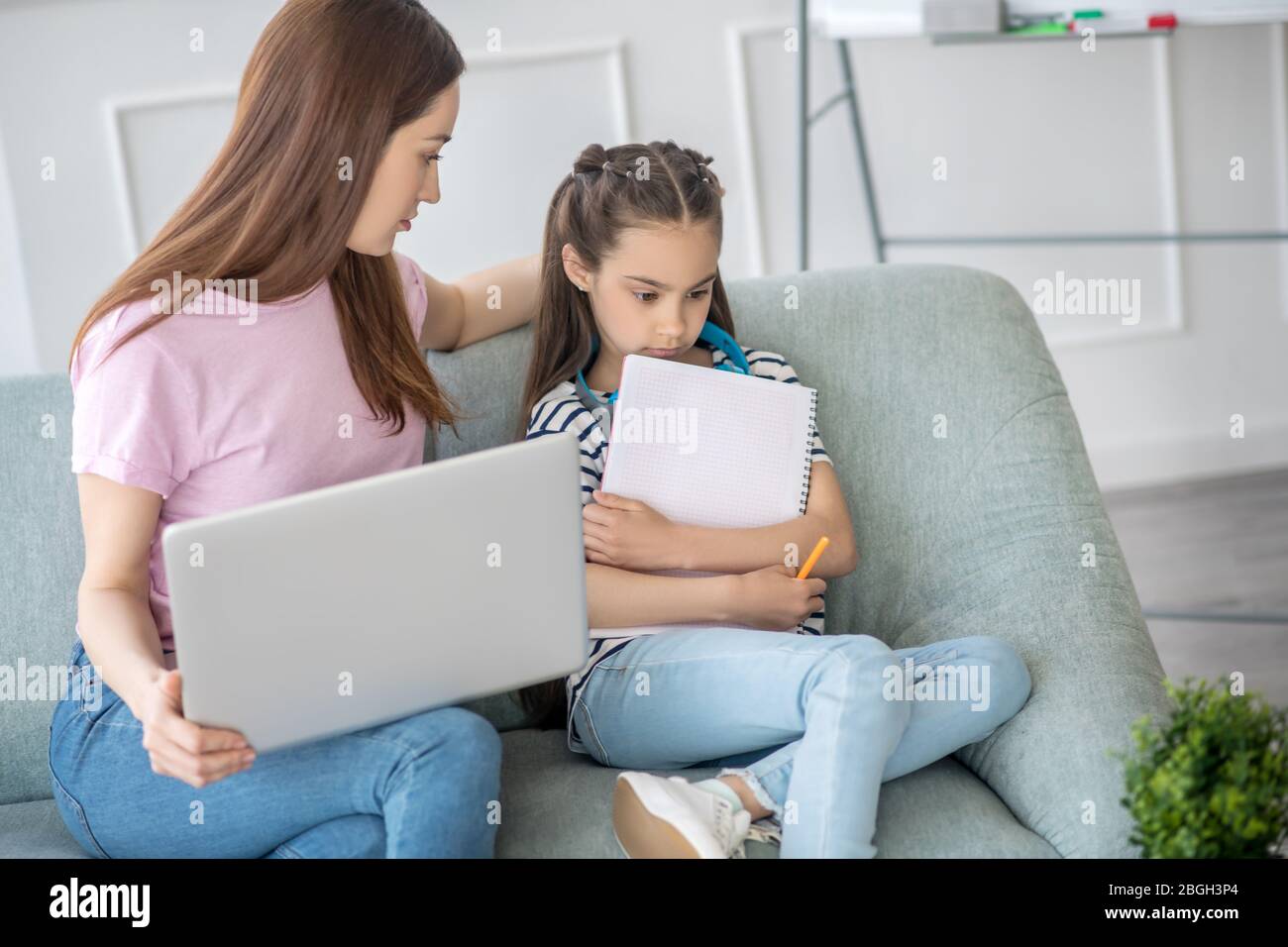 Une fille ennuyée et une maman attentionnée avec un ordinateur portable. Banque D'Images