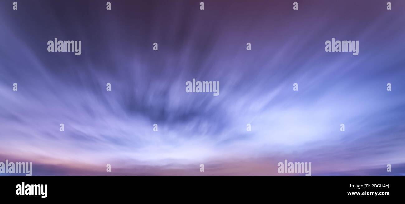 Nuages fugaces illuminés sur le ciel nocturne avec des couleurs blanches et bleues Banque D'Images