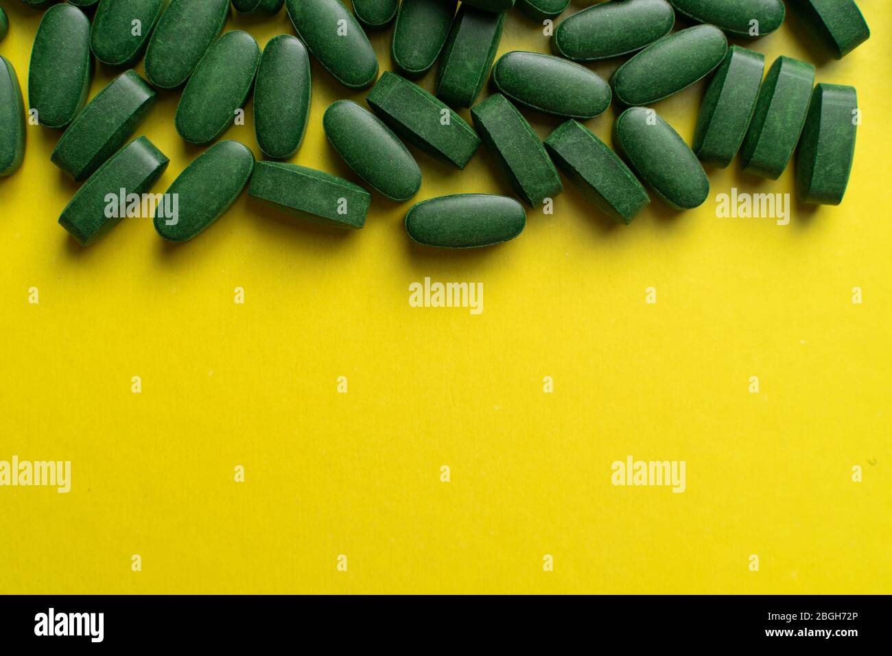 pilules vertes chlorella sur fond jaune. suppléments nutritionnels pour un régime sain Banque D'Images