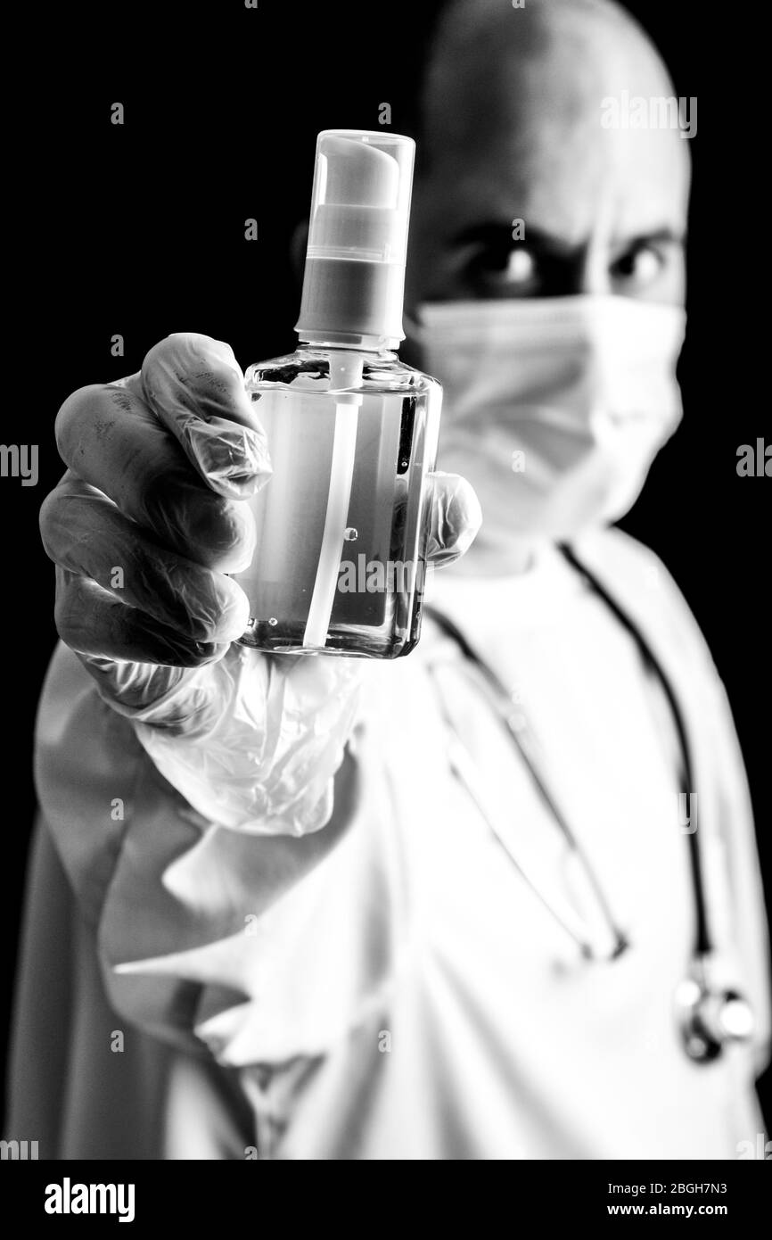 Le médecin masculin portant un masque et un stéthoscope contient un désinfectant pour les mains Banque D'Images