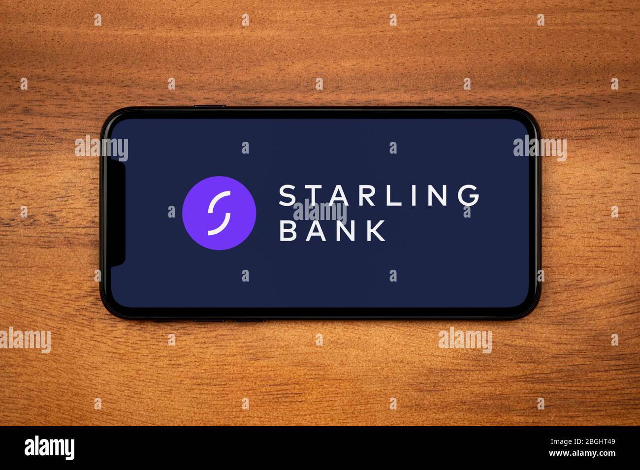 Un smartphone affichant le logo Starling Bank repose sur une table en bois ordinaire (usage éditorial uniquement). Banque D'Images