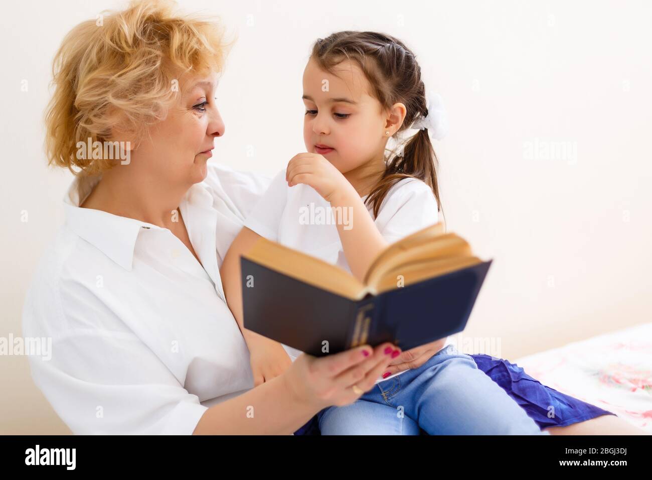Grand-mère lisant un conte à sa petite-fille de bébé. Loisirs de lecture en famille. Temps de qualité. Bonne famille s'amuser à jouer à la maison. Banque D'Images