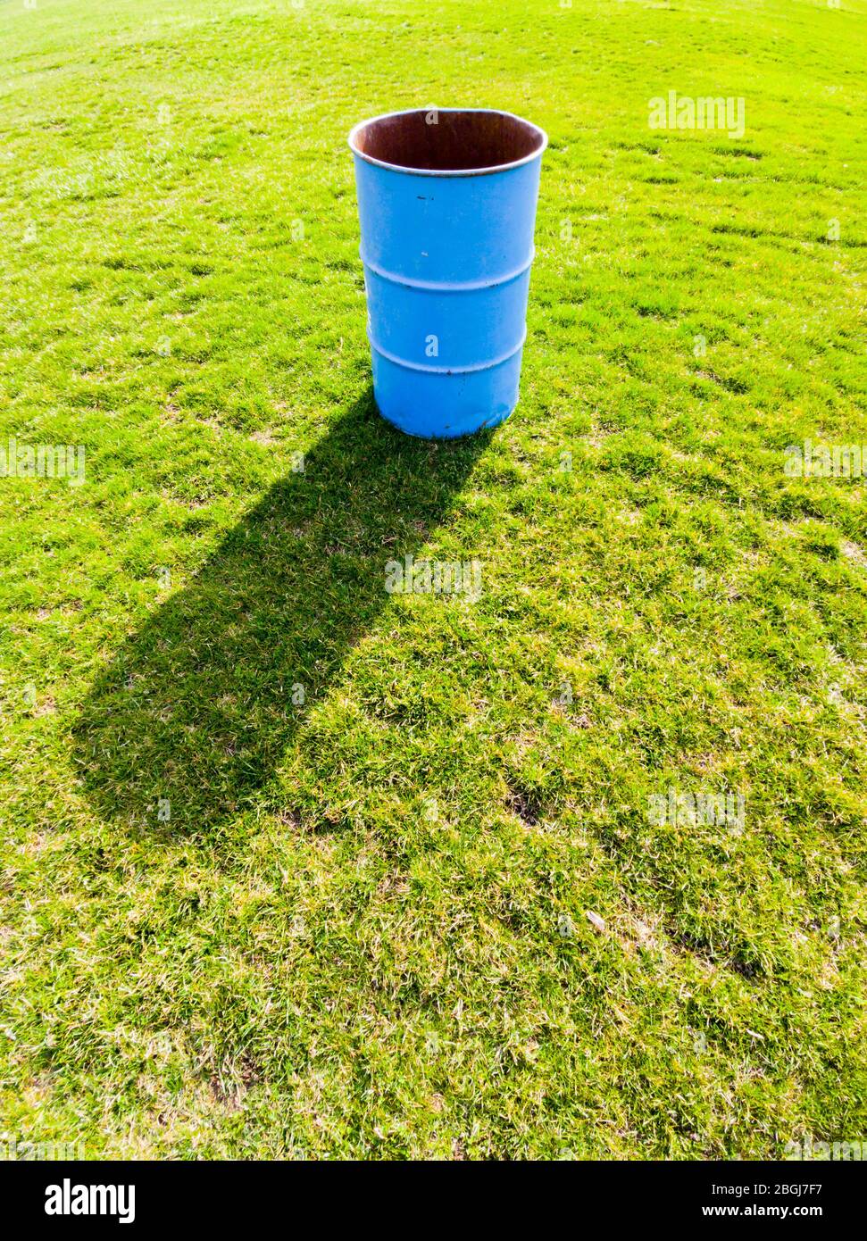 Ombre de moulage de bac en métal bleu unique sur le champ vert d'herbe. Banque D'Images