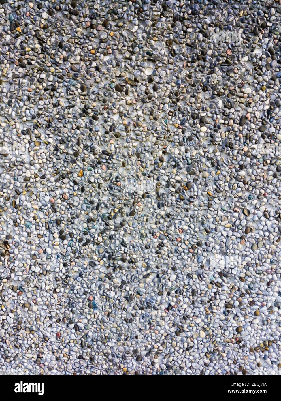 Motif abstrait de fond de galets colorés dans la paroi de ciment. Banque D'Images
