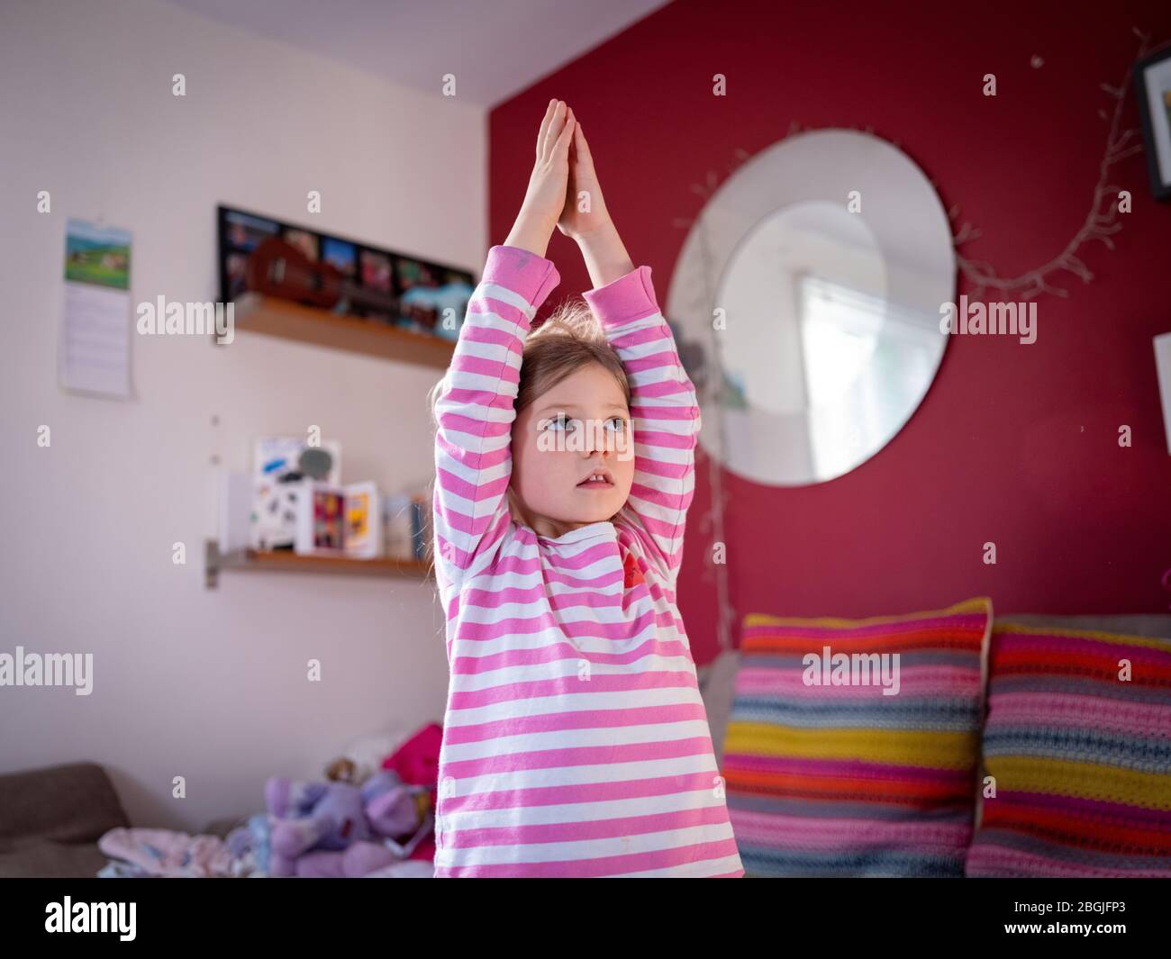 Une fille de quatre ans pratique le yoga à la maison, pendant le verrouillage du virus Cover-19. Banque D'Images