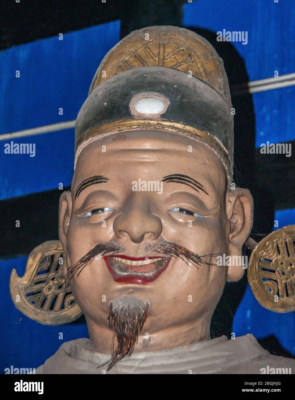 Fengdu, Chine - 8 mai 2010 : Ville fantôme, sanctuaire historique. Gros plan de visage brun souriant avec des bruns et un chapeau noirs devant un fond bleu en tant que partie Banque D'Images